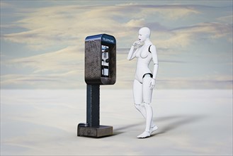 Curious robot woman examining pay telephone