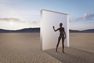 Futuristic woman touching glass wall in desert