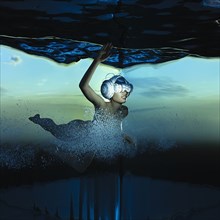 Woman swimming underwater wearing virtual reality helmet