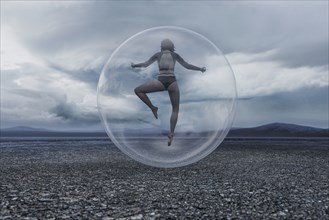 Woman floating in sphere in remote landscape