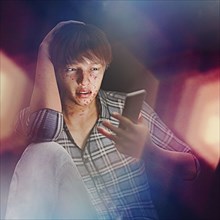 Boy with acne texting on cell phone