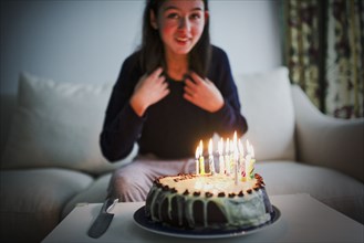Smiling mixed race girl sitting near birthday cake