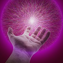 Hand of Caucasian man holding glowing sphere of purple energy