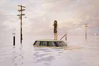 Woman standing on roof of car in flood