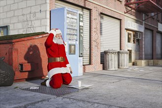 Santa kneeling on sidewalk begging