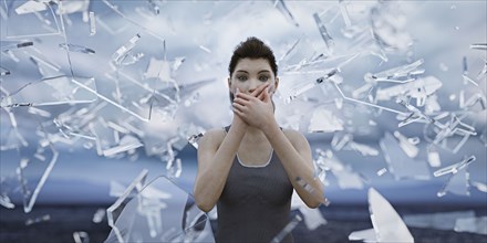 Shards of glass surrounding woman covering mouth with hands