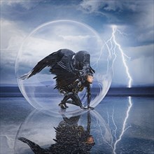 Woman with wings kneeling in sphere during lightning storm