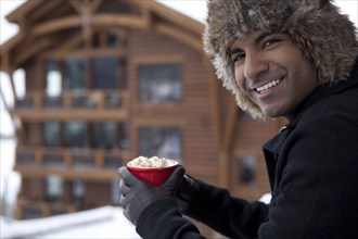 Smiling man drinking hot chocolate outdoors