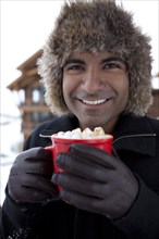 Smiling man drinking hot chocolate outdoors