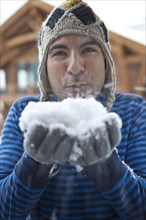 Man in cap blowing snow