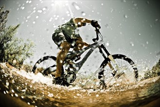 Man riding mountain bike through water