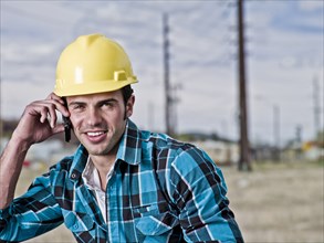 Smiling construction worker talking on cell phone