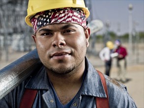 Mixed race construction worker carrying pipe
