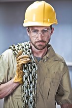 Caucasian worker in hard-hat holding chains