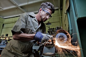 Caucasian man grinding metal in workshop