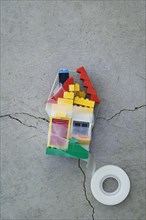 Plastic block house taped together on concrete