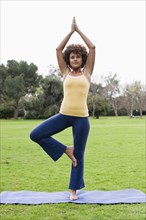Mixed race woman practicing yoga in park