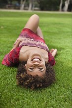 Smiling mixed race woman laying in grass