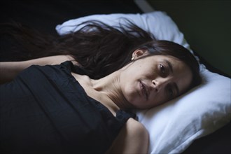 Sad mixed race woman laying in bed