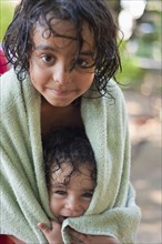 Wet mixed race boy and brother wrapped in towel