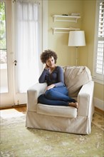 Mixed race woman relaxing in armchair