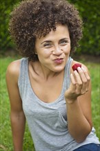 Mixed race woman eating strawberry
