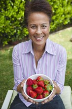 Mixed race woman holding a bowl of strawberries