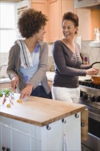 Mixed race mother and daughter cooking in kitchen