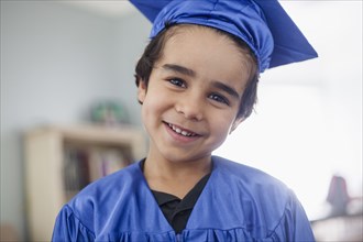 Smiling mixed race boy in graduation cap and gown