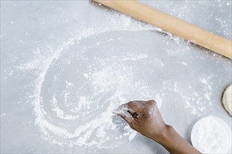 High angle view of baker sprinkling flour on counter