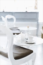 Cafe table with cups of coffee and coffee pot