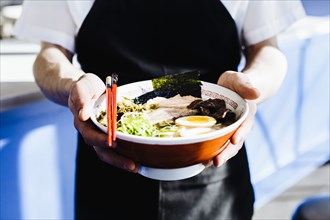 Chef holding bowl of ramen in restaurant