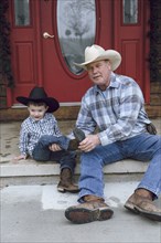 Caucasian farmer and grandson sitting on front porch