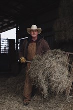 Caucasian farmer shoveling hay in barn