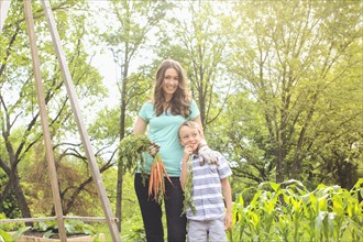 Caucasian mother and son holding carrots in garden