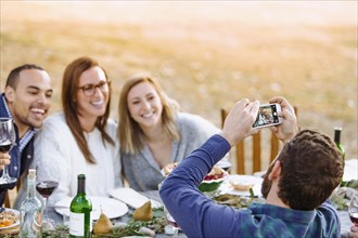 Man photographing friends at outdoor table