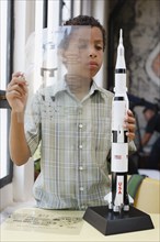 Mixed race boy building model rocket