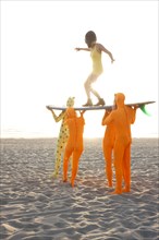 People dressed in strange costumes holding surfboard