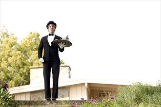 Caucasian man in tuxedo carrying tray