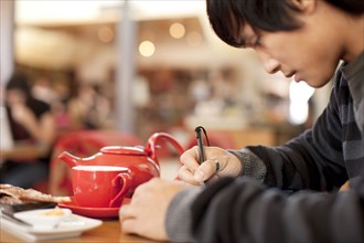 Mixed race man writing at cafe