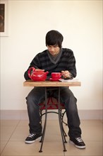 Mixed race man drinking tea and using digital tablet at cafe