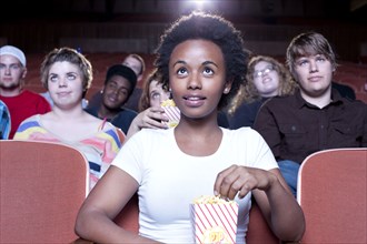 African woman eating popcorn in movie theater