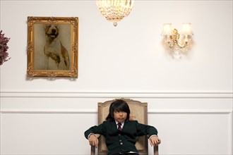 Vietnamese boy sitting on elegant chair
