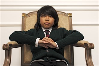 Serious Vietnamese boy sitting on elegant chair