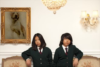 Sad Vietnamese children standing in elegant room