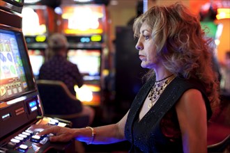 Caucasian woman playing slot machine in casino