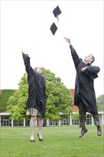 Graduates throwing graduation caps into air