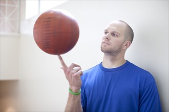Caucasian man spinning basketball on finger