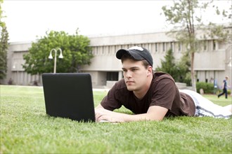Serious Caucasian man using laptop in grass