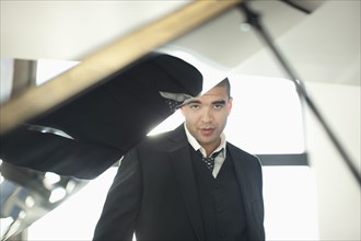Mixed race businessman standing behind piano